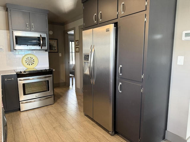 kitchen featuring light wood-type flooring, appliances with stainless steel finishes, and backsplash