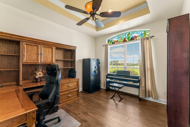 office area featuring dark hardwood / wood-style flooring, ceiling fan, a raised ceiling, and ornamental molding