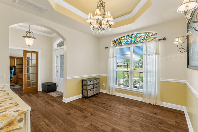 dining area with french doors, a raised ceiling, crown molding, dark hardwood / wood-style floors, and a chandelier