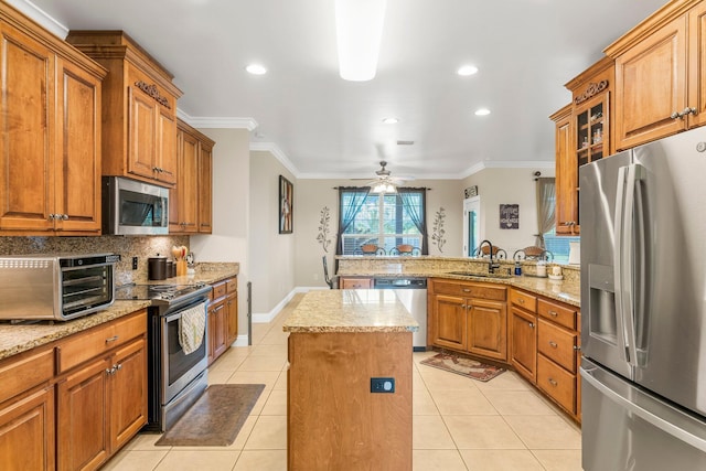 kitchen featuring stainless steel appliances, ceiling fan, crown molding, a kitchen island, and light tile patterned flooring