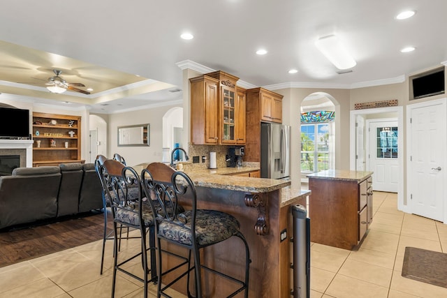 kitchen with kitchen peninsula, ceiling fan, a kitchen island, light hardwood / wood-style floors, and stainless steel fridge with ice dispenser