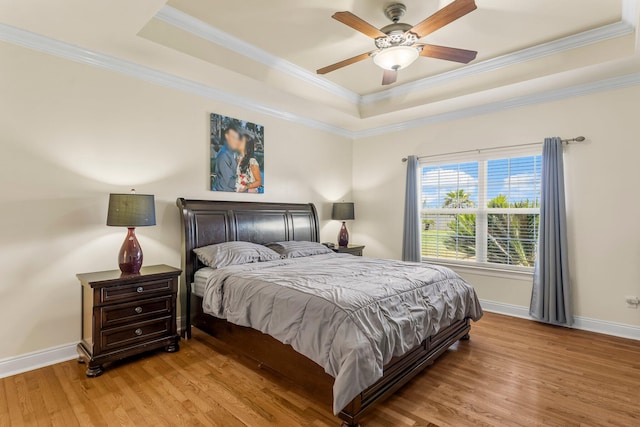 bedroom with a raised ceiling, ceiling fan, crown molding, and light hardwood / wood-style floors