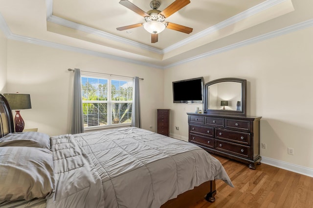 bedroom with a tray ceiling, ceiling fan, light hardwood / wood-style floors, and ornamental molding