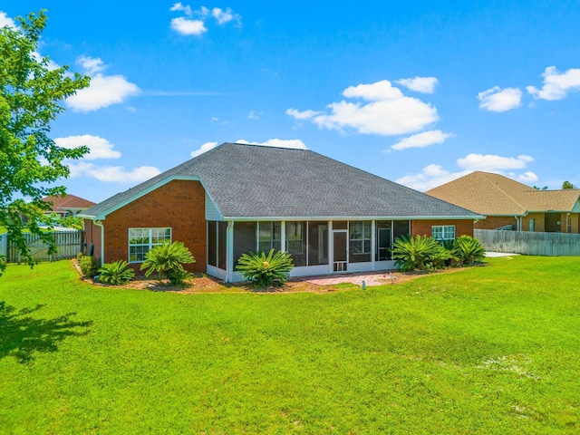 rear view of house featuring a sunroom and a lawn