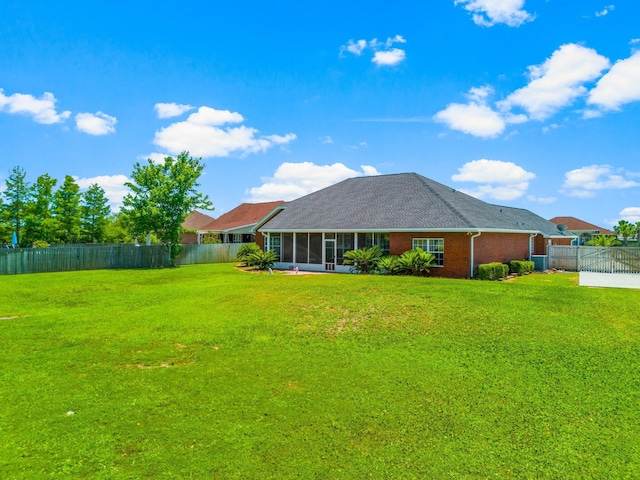 rear view of property featuring a sunroom and a lawn