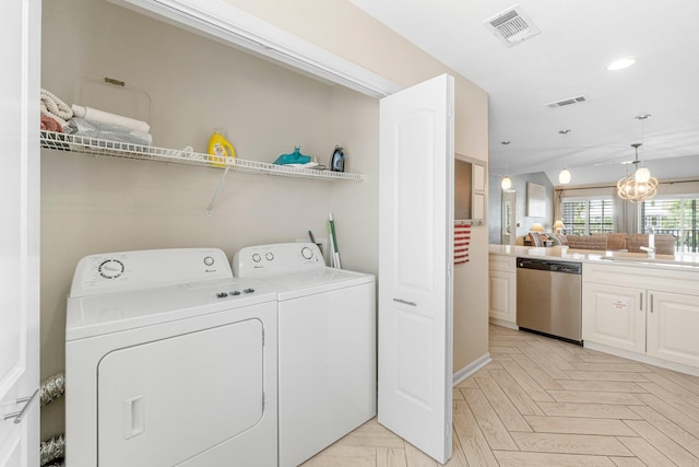 clothes washing area with sink, washer and clothes dryer, and light parquet flooring