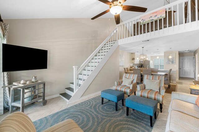 living room featuring light parquet flooring, ceiling fan with notable chandelier, and a high ceiling