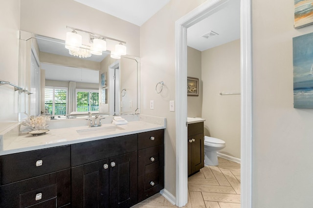 bathroom with vanity, parquet floors, and toilet