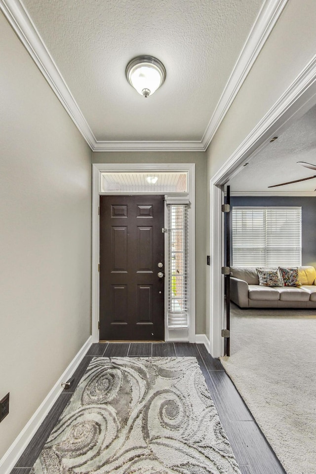 entryway with ceiling fan, dark wood-type flooring, a textured ceiling, and ornamental molding