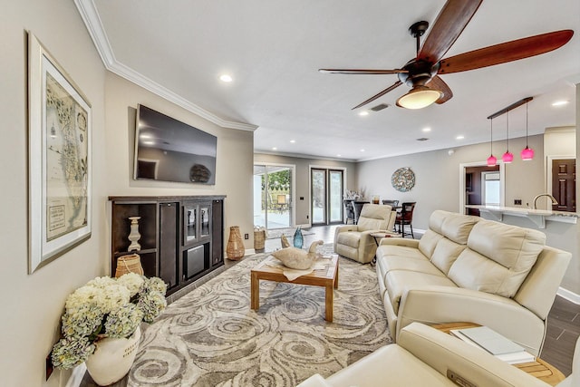 living room featuring hardwood / wood-style floors, ceiling fan, and ornamental molding