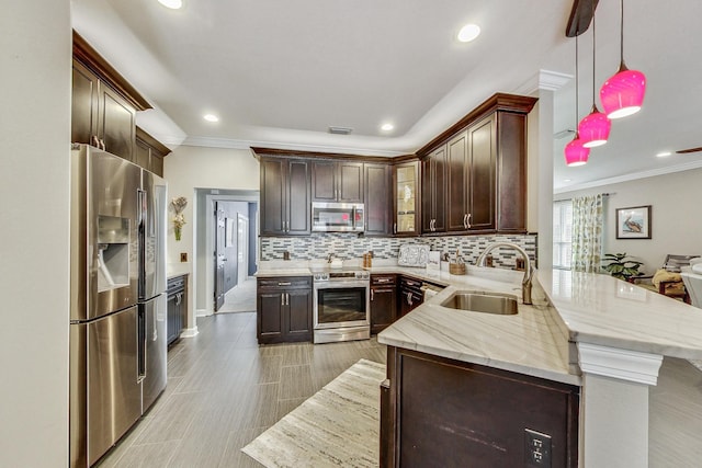 kitchen with kitchen peninsula, sink, appliances with stainless steel finishes, decorative light fixtures, and dark brown cabinets