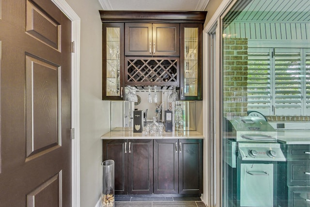 bar with dark brown cabinets and ornamental molding