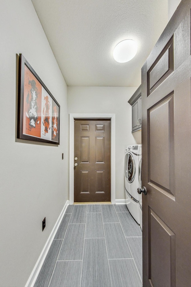 laundry room featuring washer and dryer, cabinets, and a textured ceiling