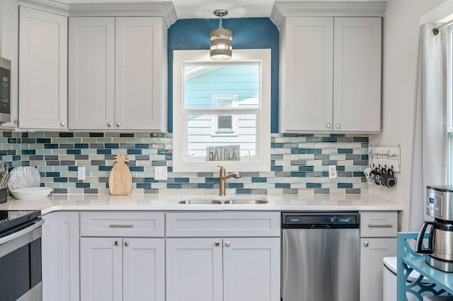 kitchen with a sink, decorative backsplash, light countertops, appliances with stainless steel finishes, and pendant lighting