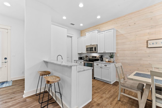 kitchen with a kitchen breakfast bar, kitchen peninsula, white cabinets, and stainless steel appliances