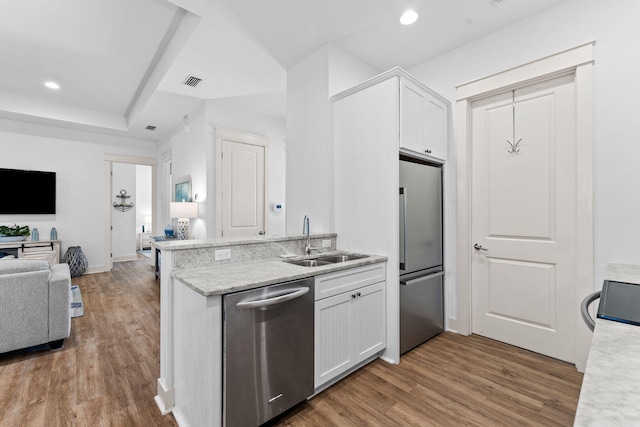 kitchen with white cabinets, sink, appliances with stainless steel finishes, and hardwood / wood-style floors