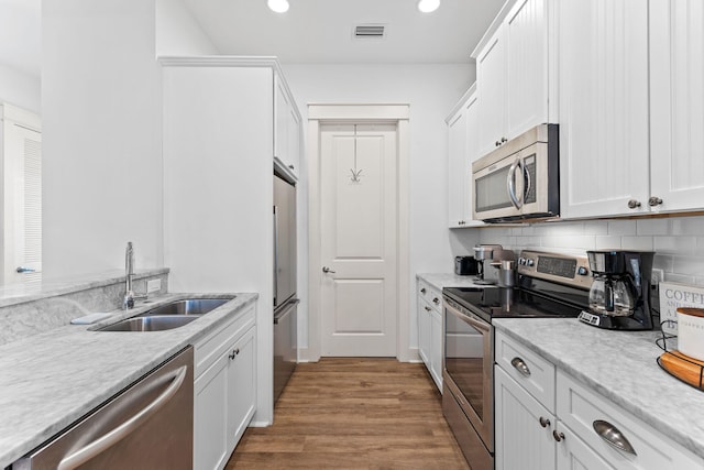 kitchen with white cabinets, backsplash, stainless steel appliances, and sink