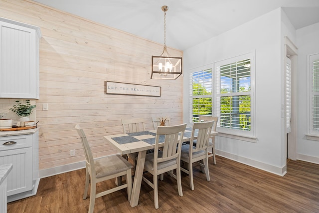 dining room featuring a notable chandelier, dark hardwood / wood-style floors, and wooden walls