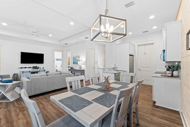 dining room featuring ceiling fan with notable chandelier, dark hardwood / wood-style flooring, and sink