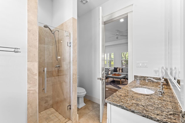 bathroom featuring ceiling fan, tile patterned flooring, toilet, vanity, and a shower with shower door