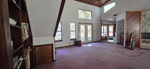 carpeted foyer entrance with high vaulted ceiling, french doors, a fireplace, and wooden ceiling