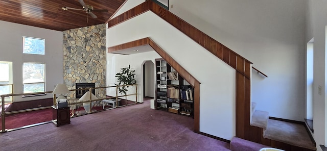 interior space with dark colored carpet, wood ceiling, a fireplace, and high vaulted ceiling