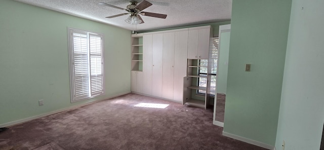 unfurnished room featuring ceiling fan, a textured ceiling, and dark colored carpet