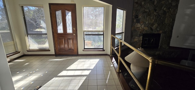 entrance foyer featuring light tile patterned floors and a stone fireplace