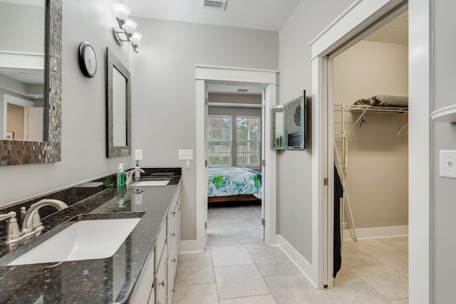 bathroom with tile patterned flooring, vanity, and a textured ceiling