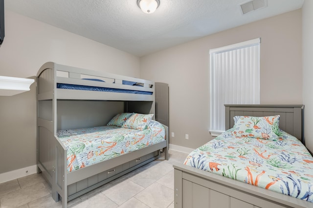 bedroom featuring light tile patterned floors and a textured ceiling