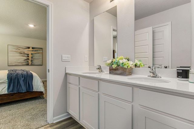 ensuite bathroom featuring double vanity, a textured ceiling, a sink, and ensuite bathroom