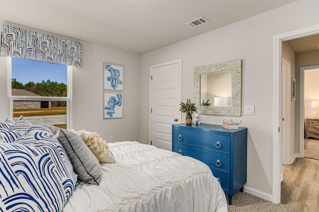 bedroom with a textured ceiling, visible vents, and baseboards