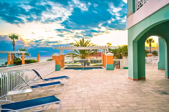 patio terrace at dusk featuring fence and a pergola