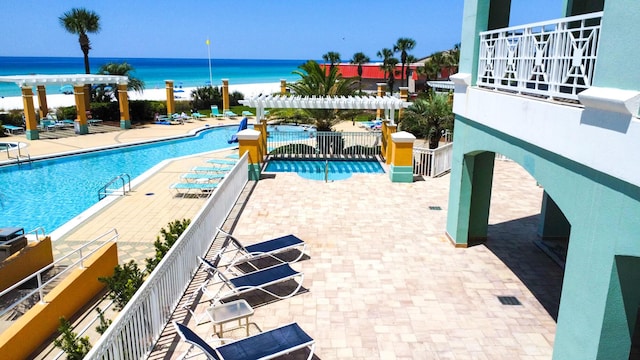 pool featuring a patio area, a pergola, and a water view