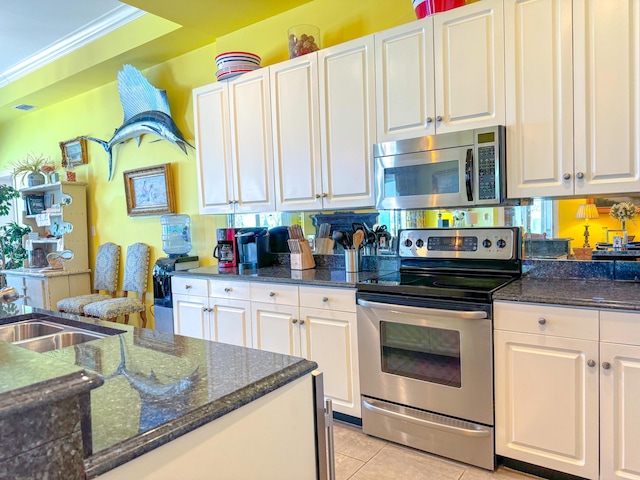 kitchen with white cabinetry, light tile patterned flooring, appliances with stainless steel finishes, and ornamental molding