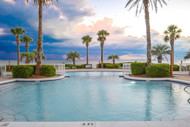 pool at dusk with fence and a community pool