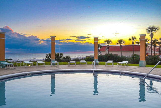 pool at dusk featuring a water view