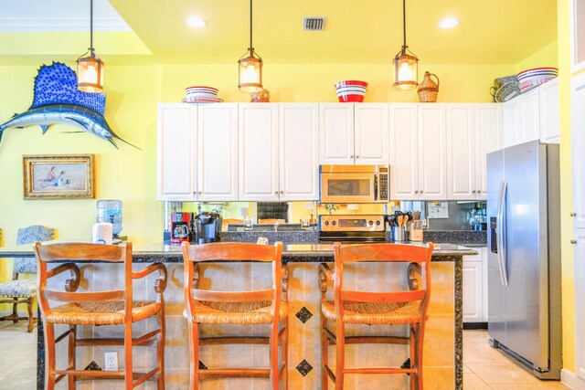 kitchen featuring a kitchen island, light tile patterned floors, appliances with stainless steel finishes, and white cabinets