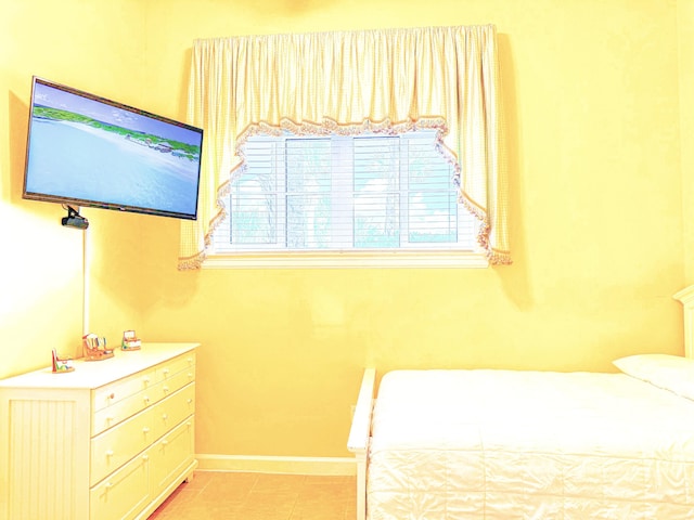 bedroom featuring light tile patterned floors, baseboards, and multiple windows