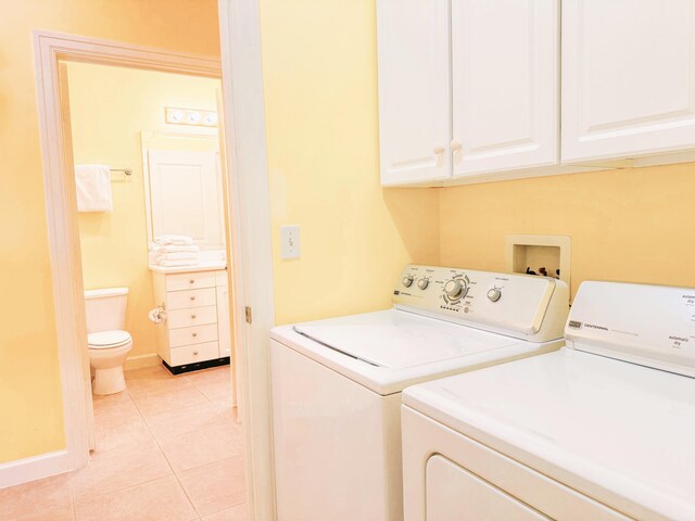 laundry room featuring light tile patterned floors, cabinets, and washing machine and dryer