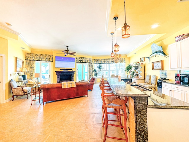 kitchen with decorative light fixtures, dark stone countertops, a kitchen bar, white cabinetry, and ceiling fan