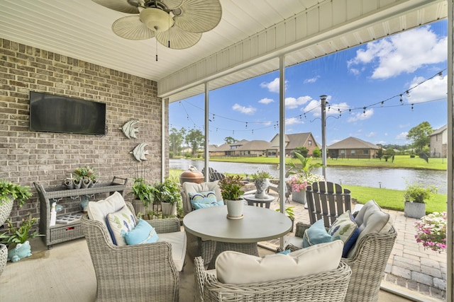 sunroom featuring ceiling fan and a water view