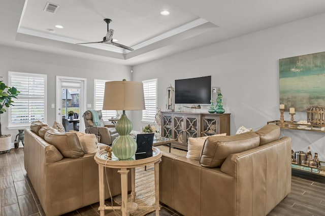 living room with a raised ceiling and ceiling fan