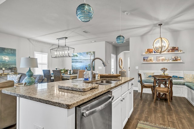 kitchen with stainless steel dishwasher, sink, pendant lighting, white cabinets, and an island with sink