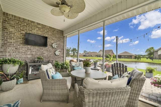 sunroom featuring ceiling fan and a water view