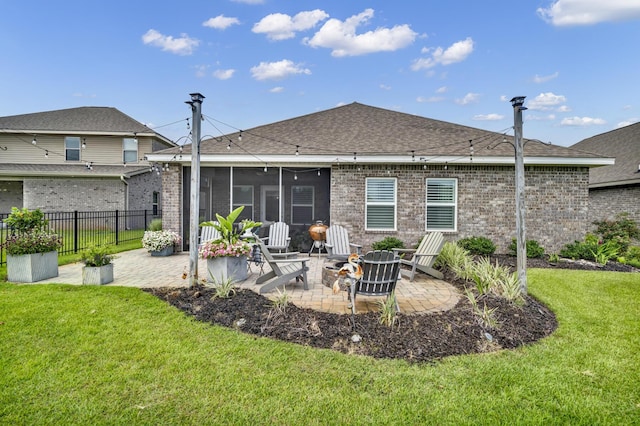 back of property featuring a lawn, a sunroom, a patio, and a fire pit