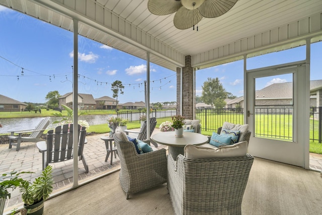 sunroom featuring ceiling fan and a water view