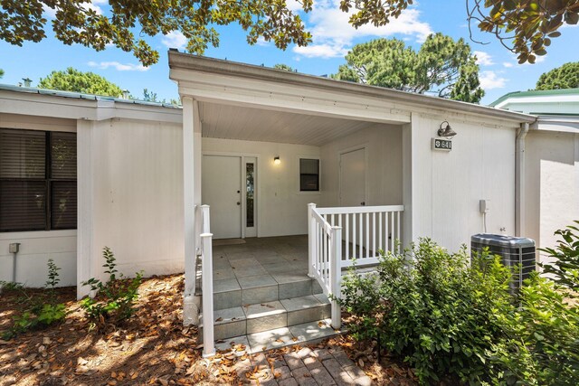 view of exterior entry with central AC unit and a porch