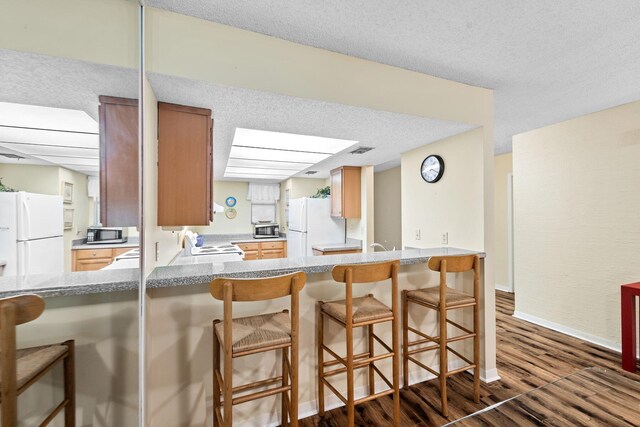 kitchen with a breakfast bar, dark hardwood / wood-style flooring, and white refrigerator