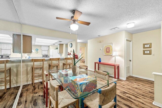 dining room featuring a textured ceiling, light hardwood / wood-style flooring, and ceiling fan